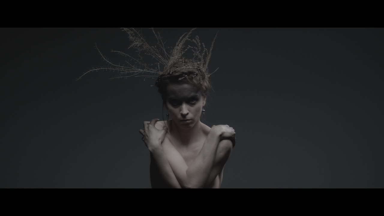 Uma mulher vestida como mãe natureza move-se lentamente em um movimento de dança