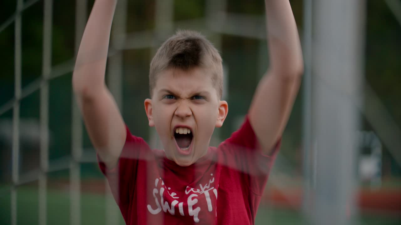 Portrait of a child in a red t-shirt celebrating a goal