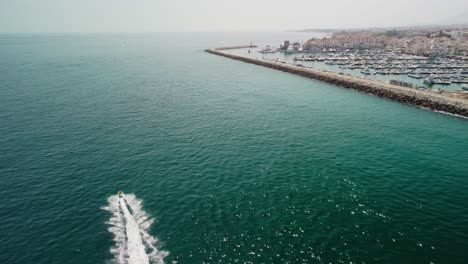 a jetski cruising in the blue waters near puerto banus, marbella, aerial view