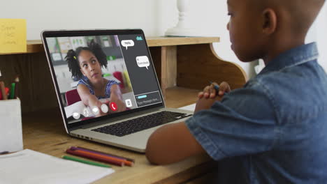 african american boy holding a pencil having a video call on laptop at home