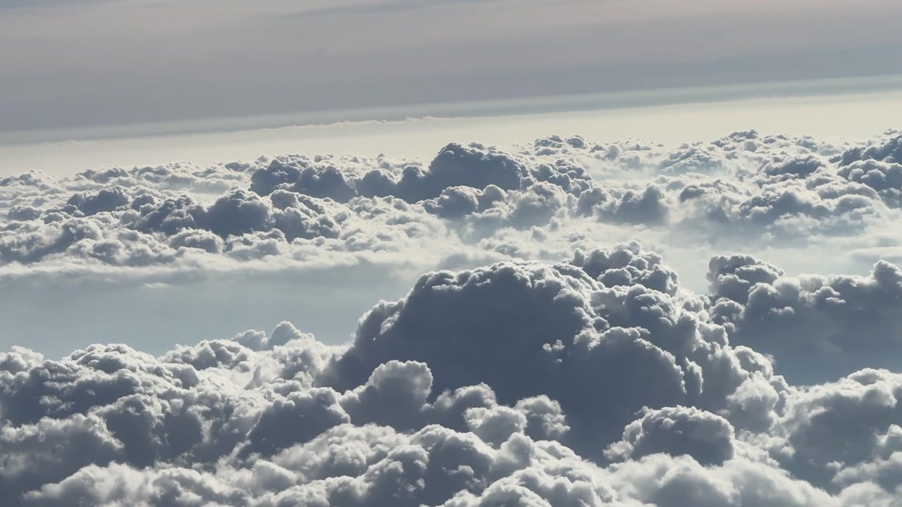 Un vasto mare di nuvole soffici illuminate dalla luce del sole, che crea un'atmosfera serena ed eterea. Ideale per l'uso in documentari di viaggio o contenuti relativi al meteo.