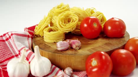 tomatoes and raw pasta on chopping board