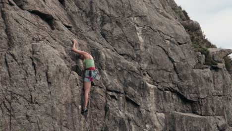 Strong-woman-climbing-rocky-wall,-back-view