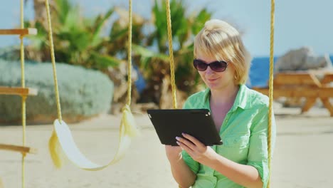 Eine-Touristin-Genießt-Das-Tablet-Auf-Einer-Schaukel-Sitzend