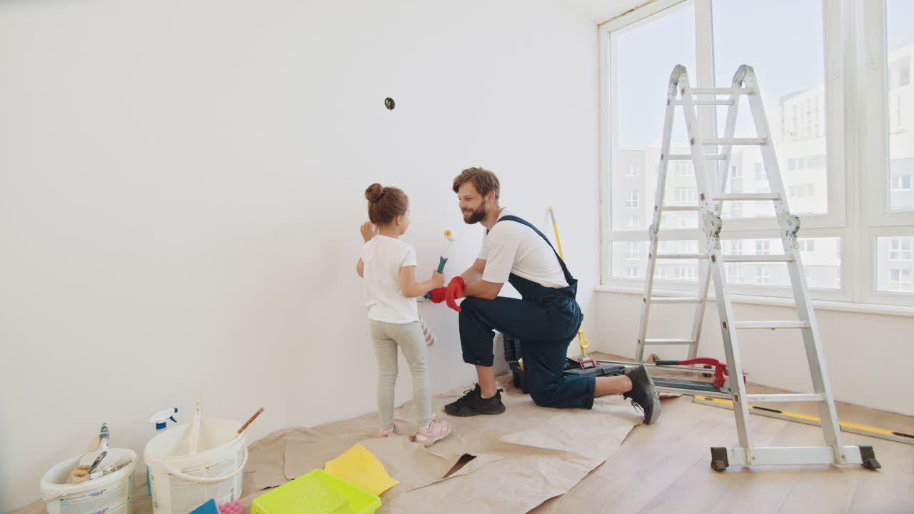ojciec i córka malują razem pokój.