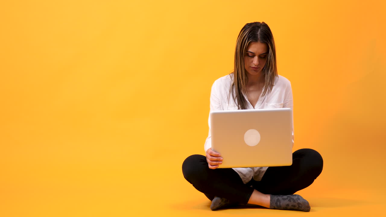 Woman sitting cross-legged using laptop