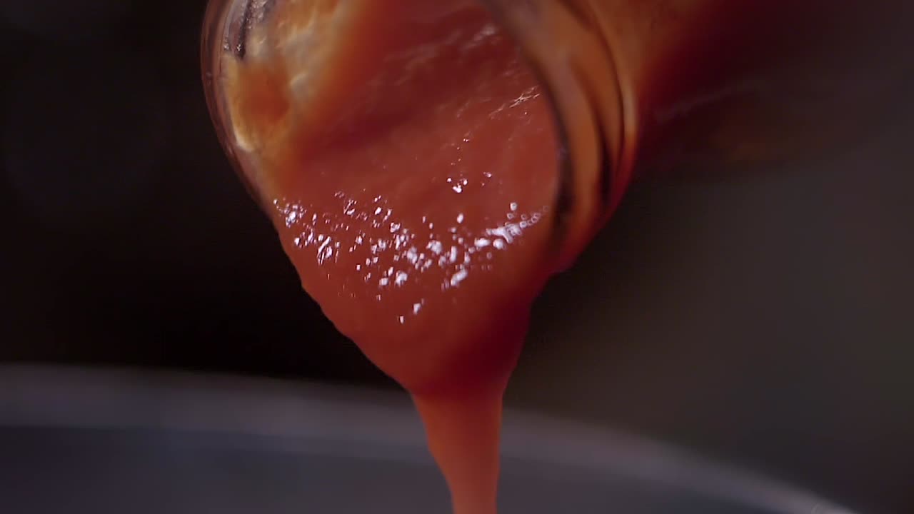 primer plano de salsa de tomate rojo vertido de botella de vidrio