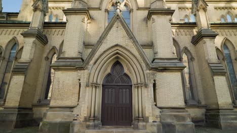 gothic cathedral side porch dark wooden entrance door archway with brick buttresses