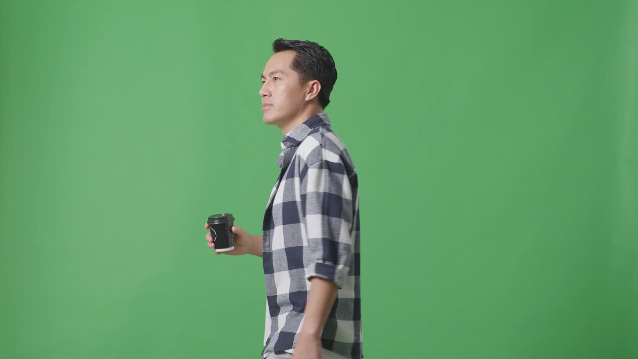 녹색 스크린 배경 에 산책 하고 커피 를 마시는 아시아인 의 측면 시각