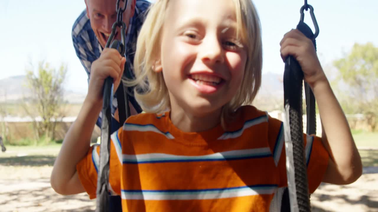 아버지 가 놀이터 4k 에서 아들 을 스 ⁇  으로 밀고 있다