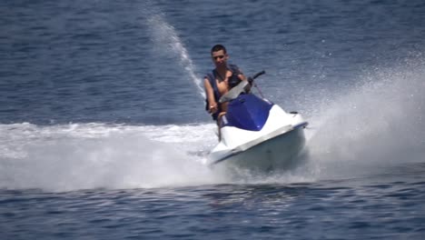 young man riding fast high speed jetski in summer sea in slow motion action shot