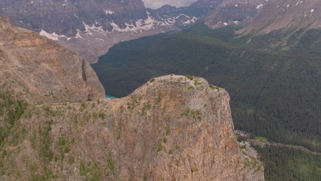 aerial dolly in of emerald lake moraine between pine tree forest and canadian rockies at banff national park, alberta, canada