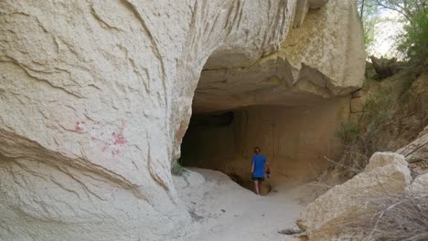 una mujer excursionista explora la cueva de roca, el sendero del valle de las rosas, capadocia.