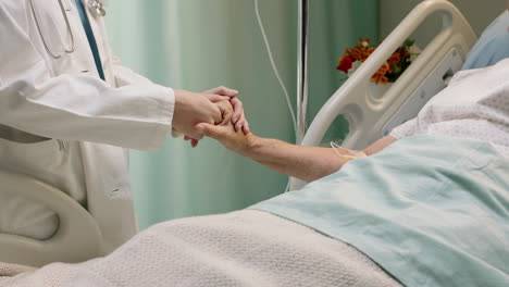 doctor holding hand of old woman in hospital bed comforting elderly patient hospitilized recovering from illness medical professional at bedside giving encouragement health care support