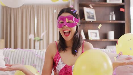 video of smiling biracial woman in pink party mask and dressed in pink dress