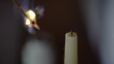 old fashioned candle lit by branch