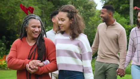 at christmas, diverse family enjoying festive walk in park, smiling and holding hands together