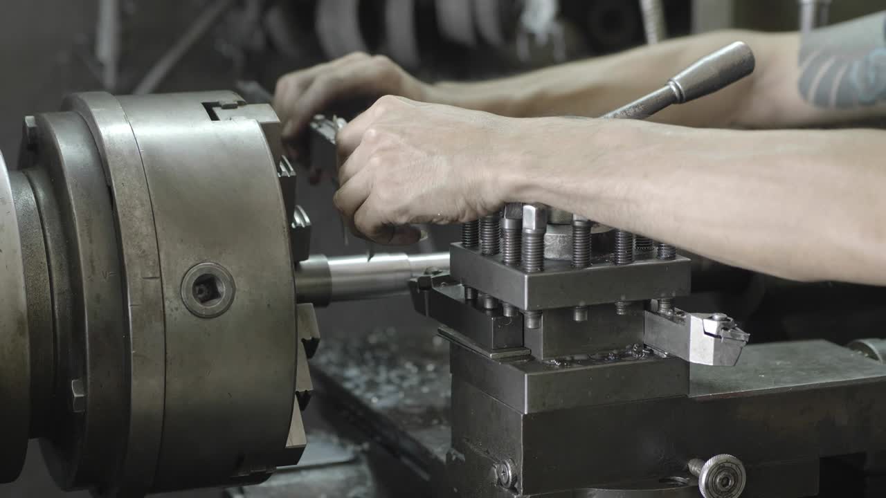 manos de hombres con una pinza de vernier midiendo el tamaño de los detalles en la pieza de trabajo en la máquina de torno en la fábrica industrial. movimiento lento
