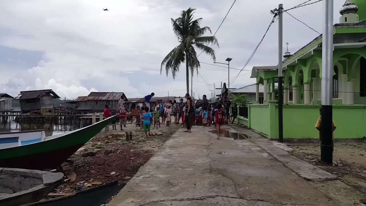 인도네시아, 아시아, 라자 암팟, 미소올에 있는 미소올 마을에서 드론을 향해 달리는 아이들