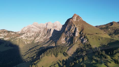 Aerial-shot-of-Swiss-alps-and-a-lake-situated-in-the-valley-near-the-forest