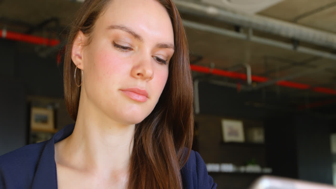 vista frontal de una joven mujer de negocios caucásica trabajando en una tableta digital en una oficina moderna 4k