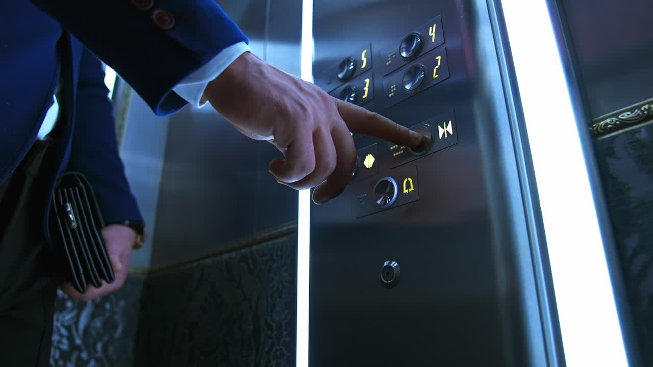 Businessman in lift. Male's hand pressing button to start moving inside the elevator. Man touches elevator button in hotel or high-rise building.
