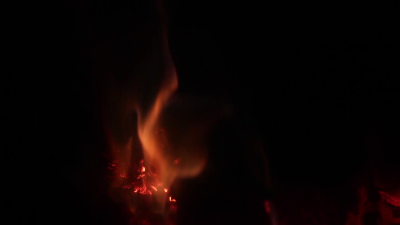 Fire going out with embers and coals illuminated in wood stove