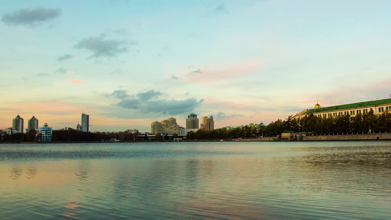 평온 한 물 에 반사 된 해 가 지는 도시 풍경