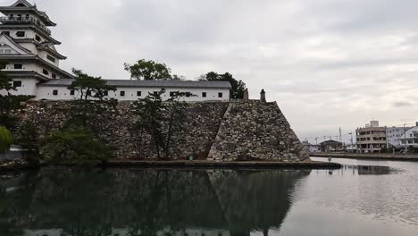 view over steep castle walls and the white building of imabari samurai castle in japan