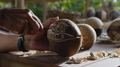 close-up of hands carving intricate patterns into a coconut shell