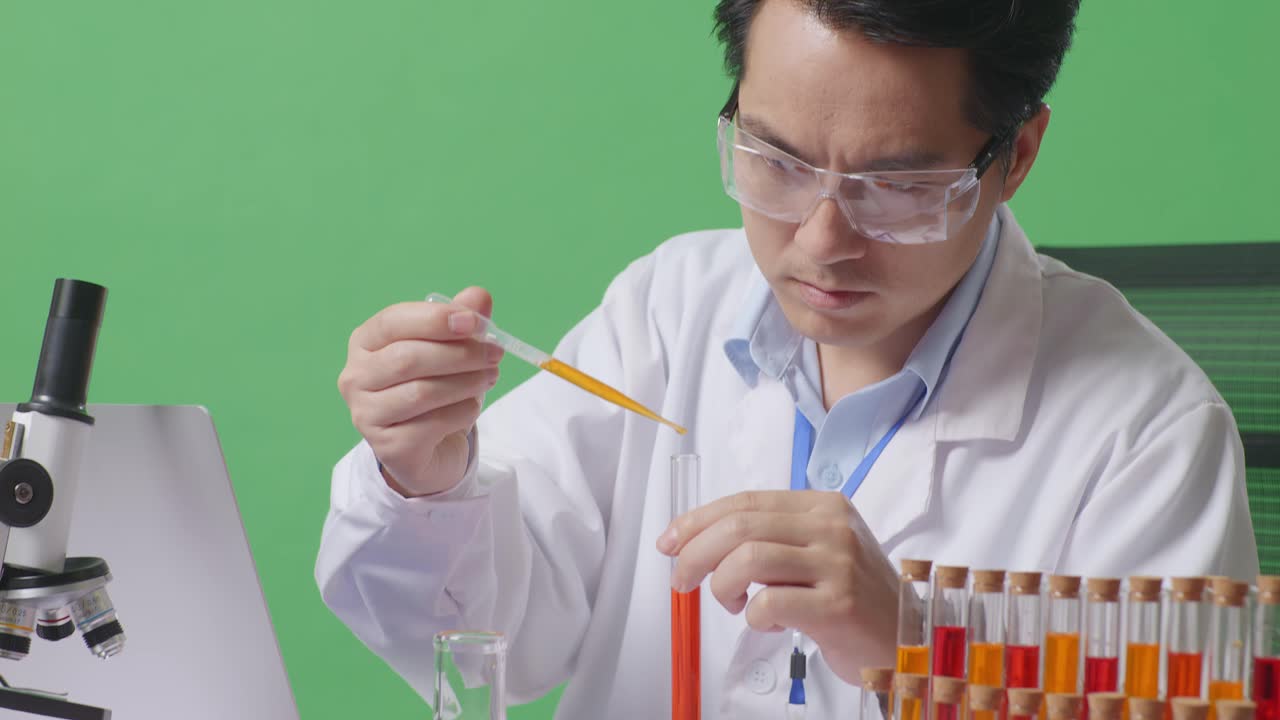 Close Up Of Side View Of Asian Man Scientist Making Experiment With Test Tube And Screaming Goal Celebrating Typing On A Laptop On The Table With Microscope In The Green Screen Background Laboratory