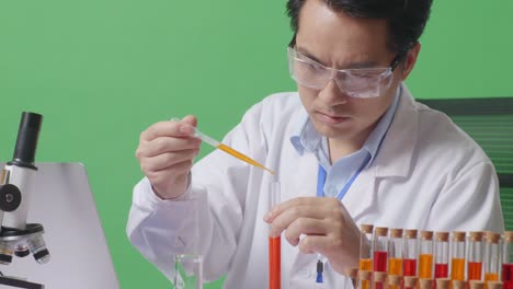 close up of side view of asian man scientist making experiment with test tube and screaming goal celebrating typing on a laptop on the table with microscope in the green screen background laboratory