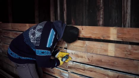 worker unscrewing screw from wood with handheld drill