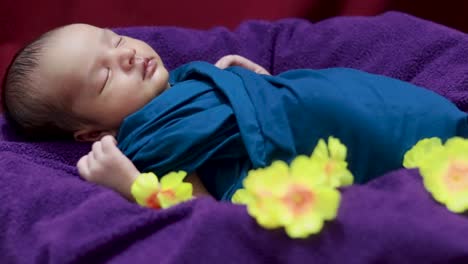 Süßes-Neugeborenes-Baby,-Das-In-Babywickel-Mit-Blumen-In-Einzigartigem-Stil-Aus-Der-Oberen-Winkelaufnahme-Schläft