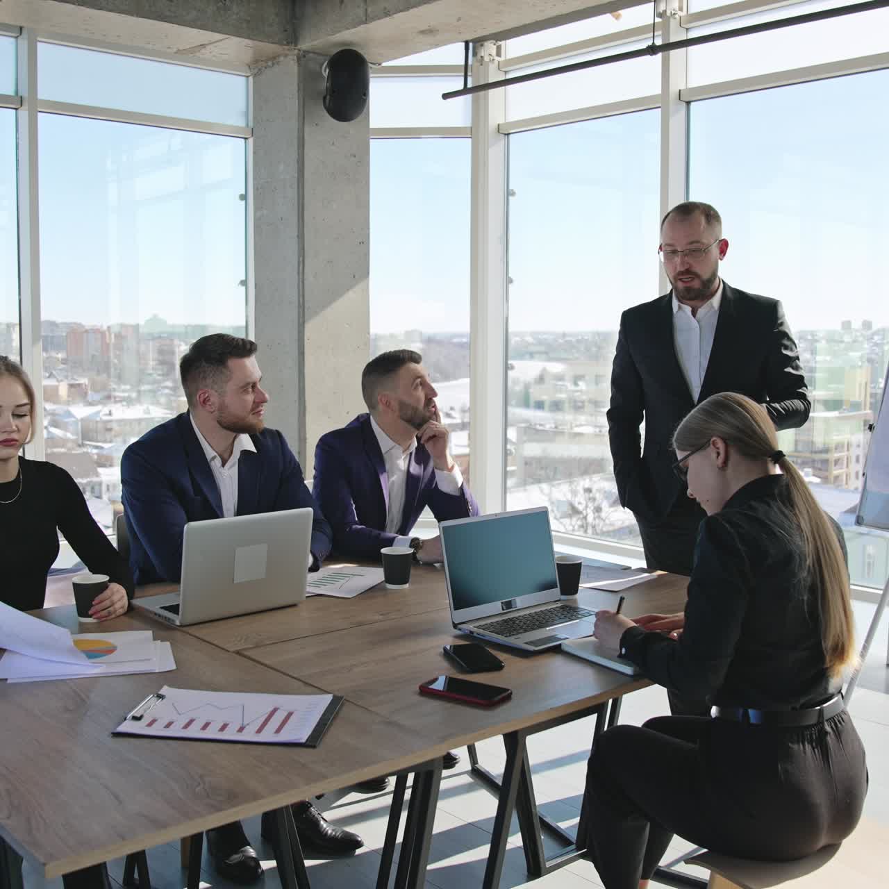 Team meeting in the spacious office. Business discussion and brainstorming with collegues. Coworkers of both genders having a meeting in the office