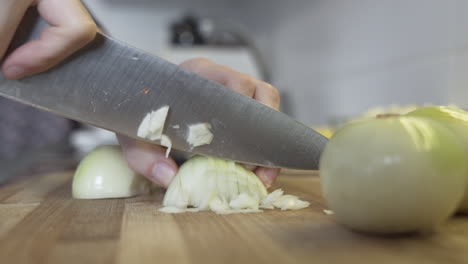 Slow-motion-close-shot-as-cutting,-chopping-an-onion-in-the-kitchen-with-a-huge-knife
