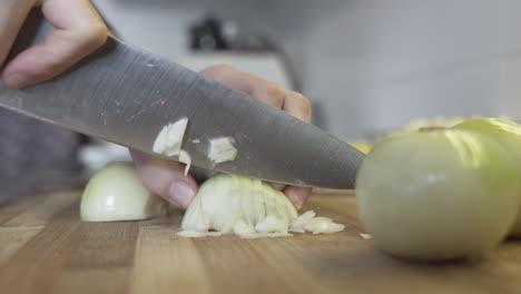 toma cercana en cámara lenta como cortando, picando una cebolla en la cocina con un cuchillo enorme