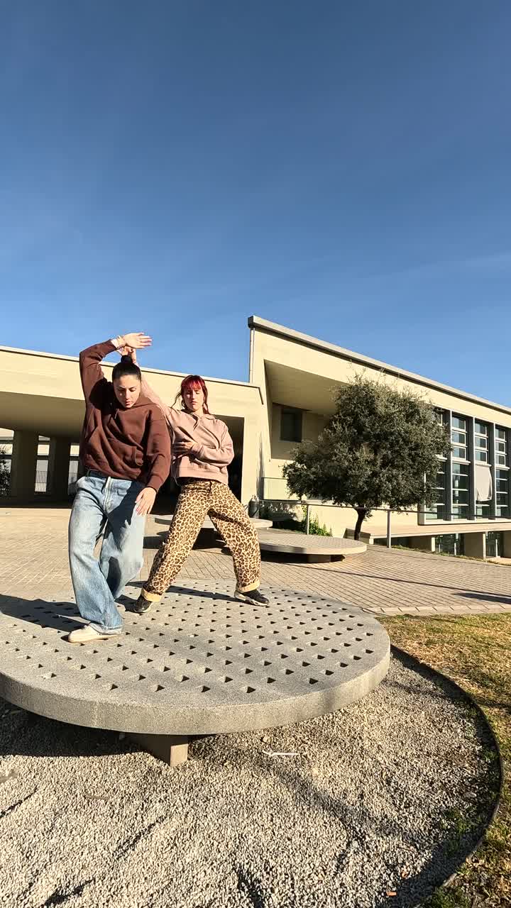 Giovane coppia che balla una coreografia all'aperto nel campus universitario.
