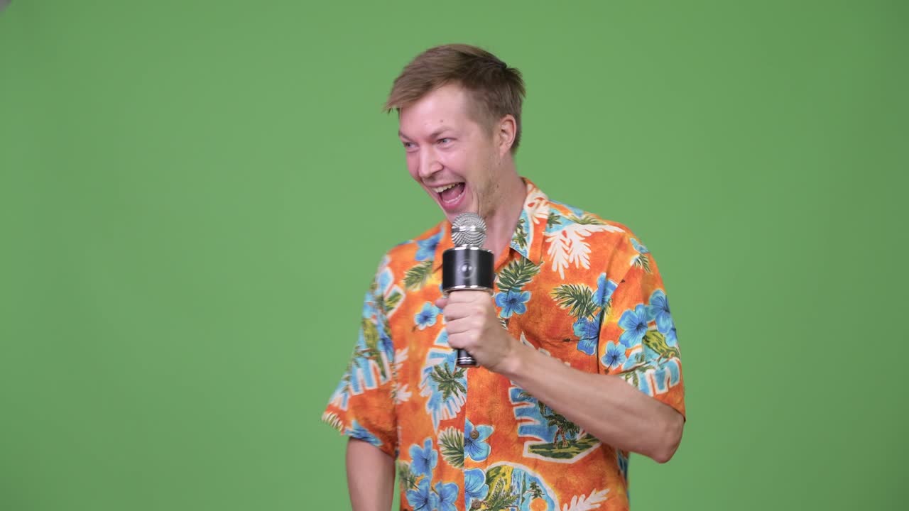 Young handsome tourist man talking on microphone and showing something