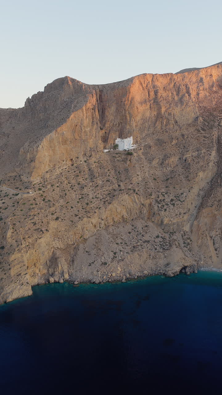 Holy Monastery of the Virgin Mary Chozoviotissa, The Panagia Hozoviotissa Monastery on steep cliff above Aegean sea at sunrise, Amorgos Island, Aerial vertical shot