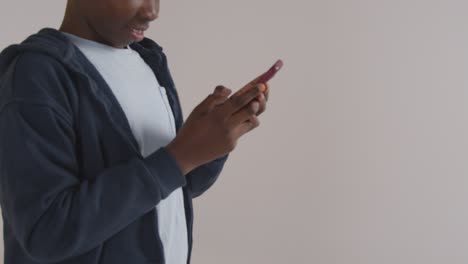 studio portrait of excited boy on asd spectrum gaming on mobile phone against white background 3