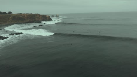 aerial drone shot following wave flying backwards on a cold, dark day in pichilemu, chile-4k