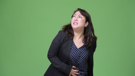 una hermosa mujer de negocios asiática madura con dolor de estómago.