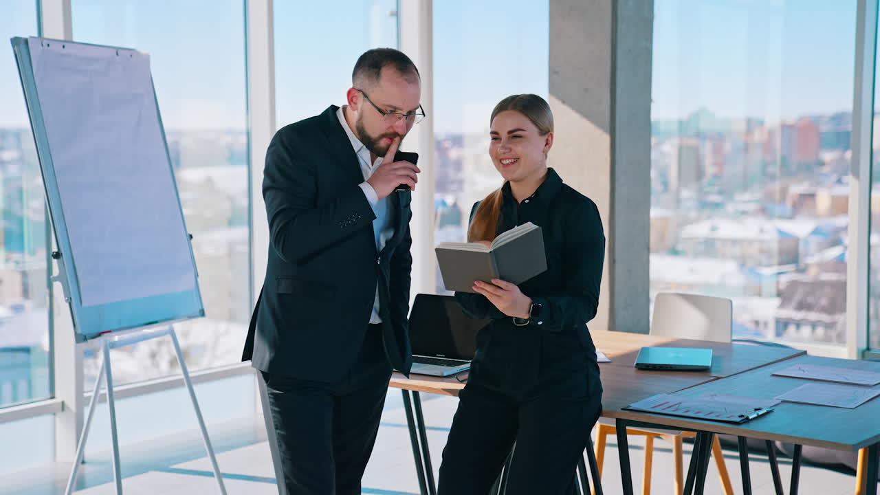 Friendly business workers indoors. Man in suit and beautiful woman having a conversation about business in modern office.