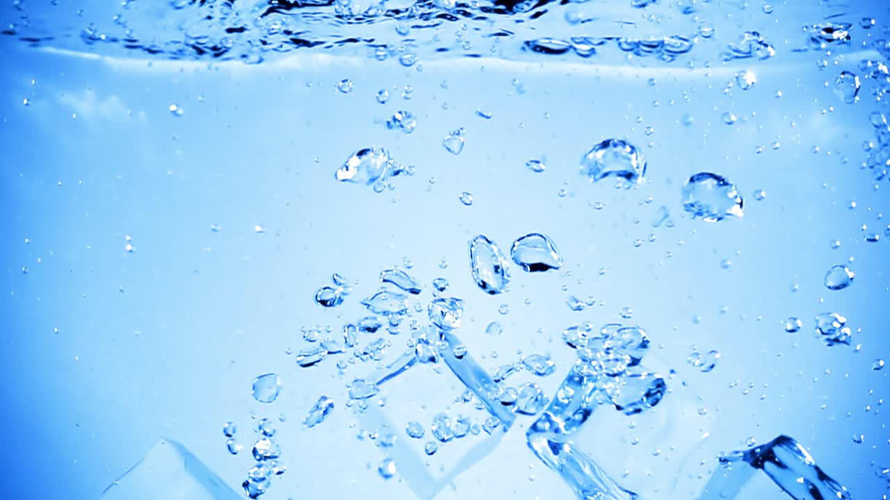 얼음 큐브가 공기 거품으로 물에 떨어집니다.