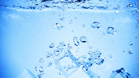 ice cubes dropped into water with air bubbles.