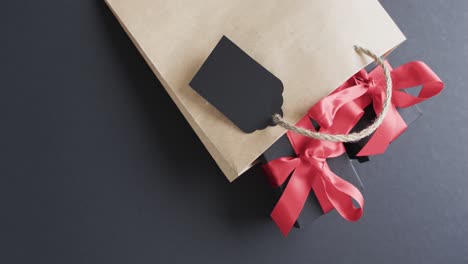 video of gift bag, gift tag and gift boxes with red ribbon and copy space on black background