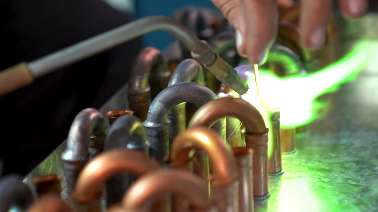 Worker Using A Blowtorch To Solder Plumbing Copper Pipes During Manufacturing Process, Close Up Shot.