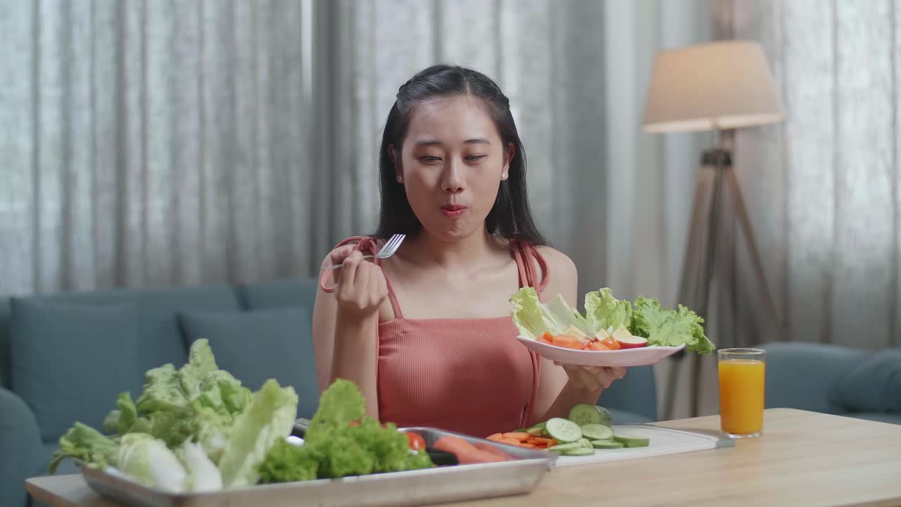 미소 짓는 아시아 여성은 건강한 음식을 먹고 집에서 카메라를 보는 것을 즐긴다.
