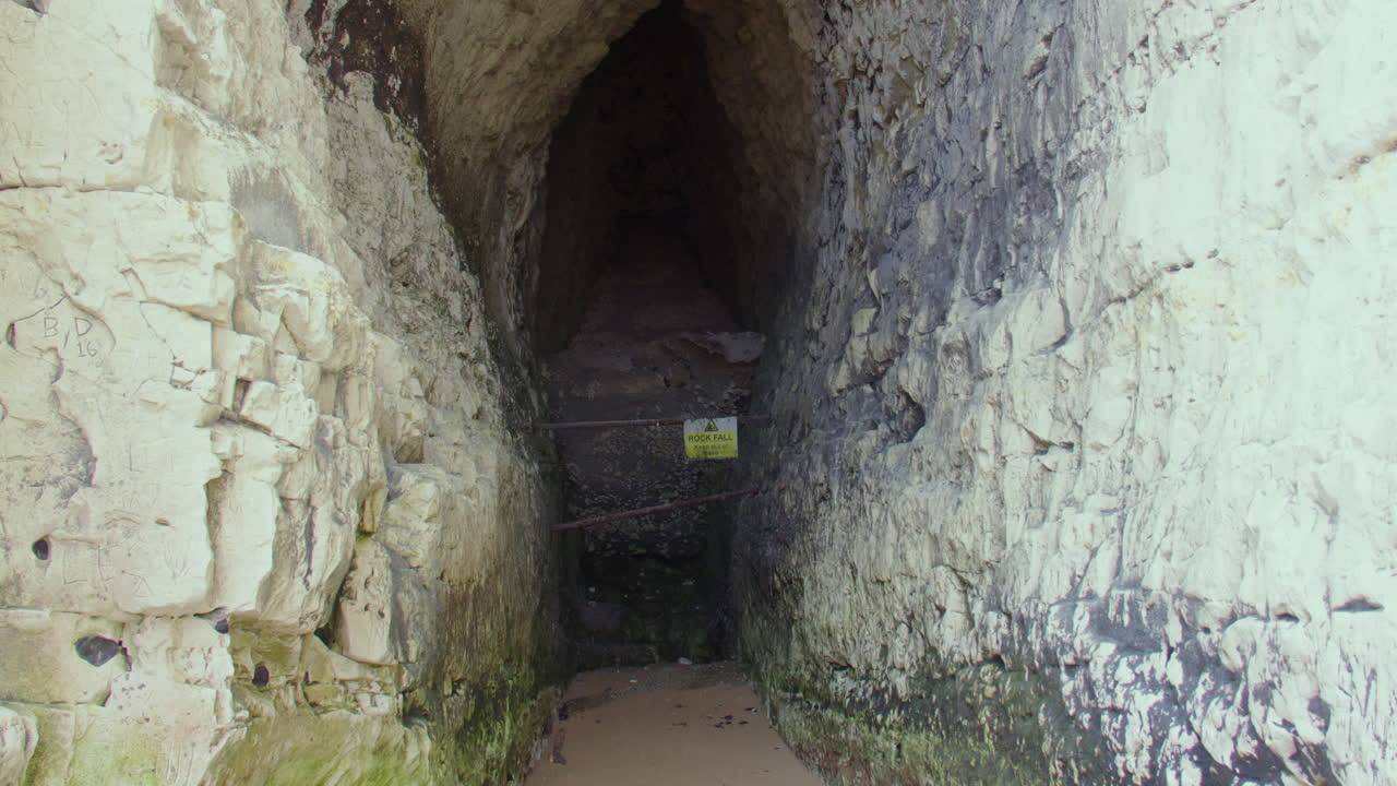 Zoom lento em uma caverna em falésias de calcário na baía da praia de Kingsgate. Na maré baixa